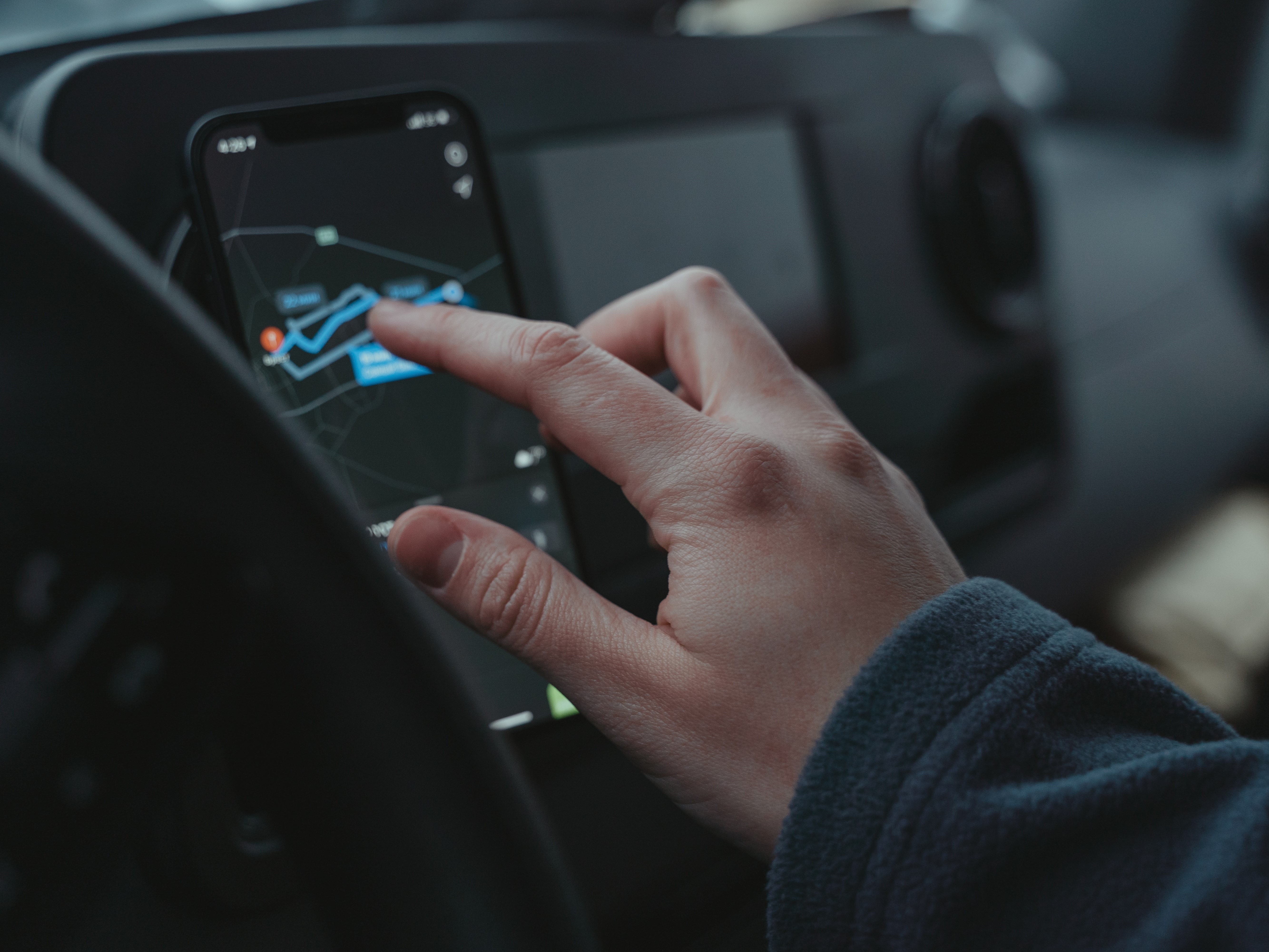 Hand, die Ortungssystem mit Smartfon im Auto bedient